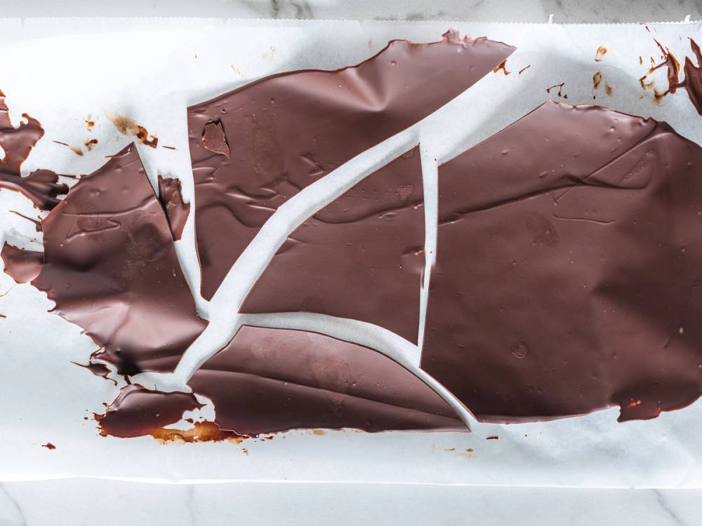 Et stykke sjokoladeseil som er delvis spist opp, med smeltet sjokolade rundt på et hvitt underlag.