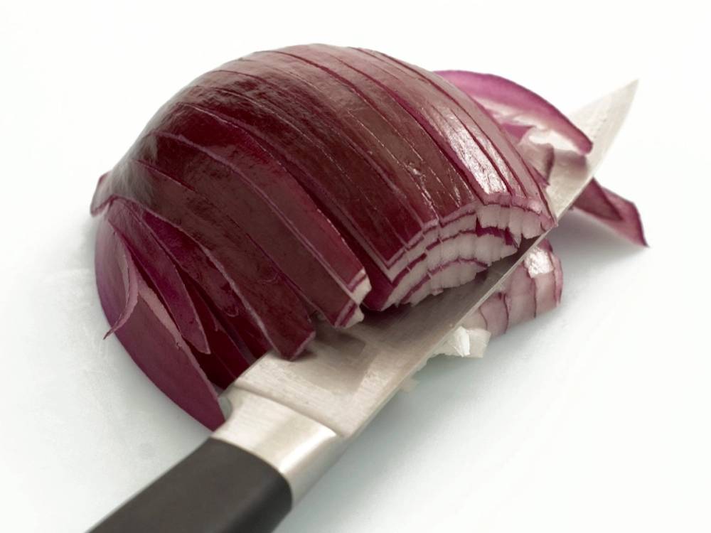 Hakket rødløk på et skjærebrett med kniv, klar til bruk i wok.