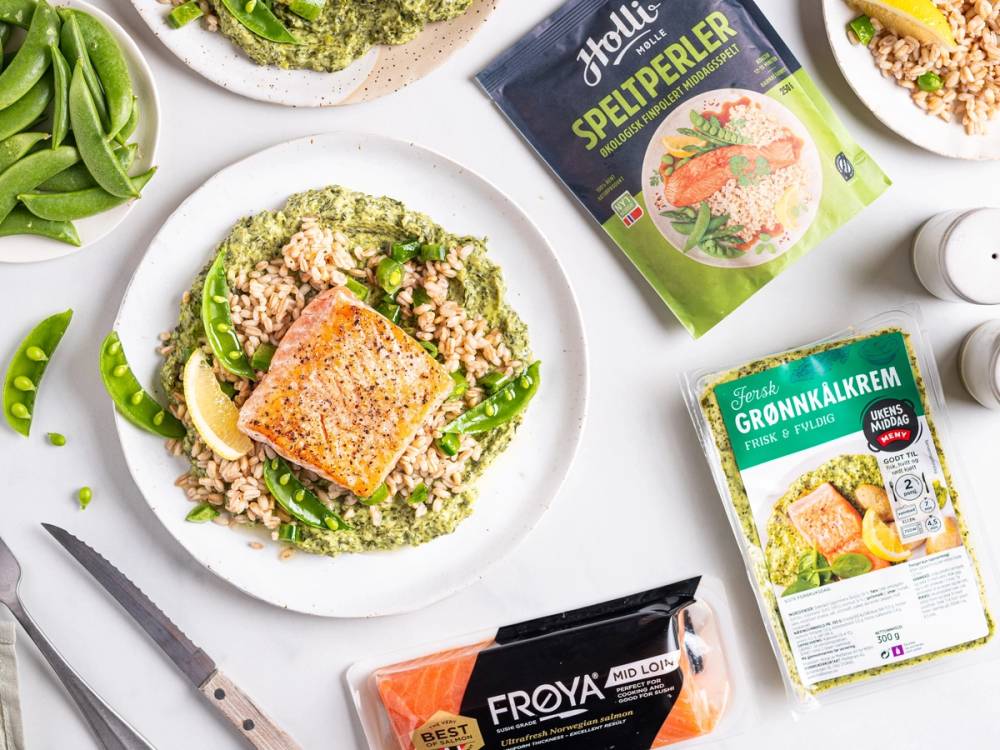 En tallerken med laks med grønnkålkrem og quinoa, omgitt av ulike matvarer og emballasje på et kjøkkenbord.