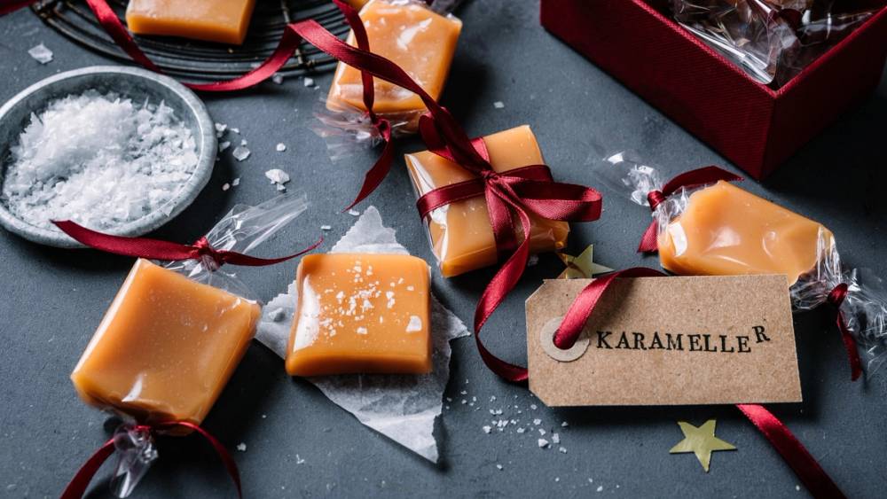 Fløtekarameller pakket inn i cellofan med røde bånd og en liten tagg med teksten 'Karameller'.