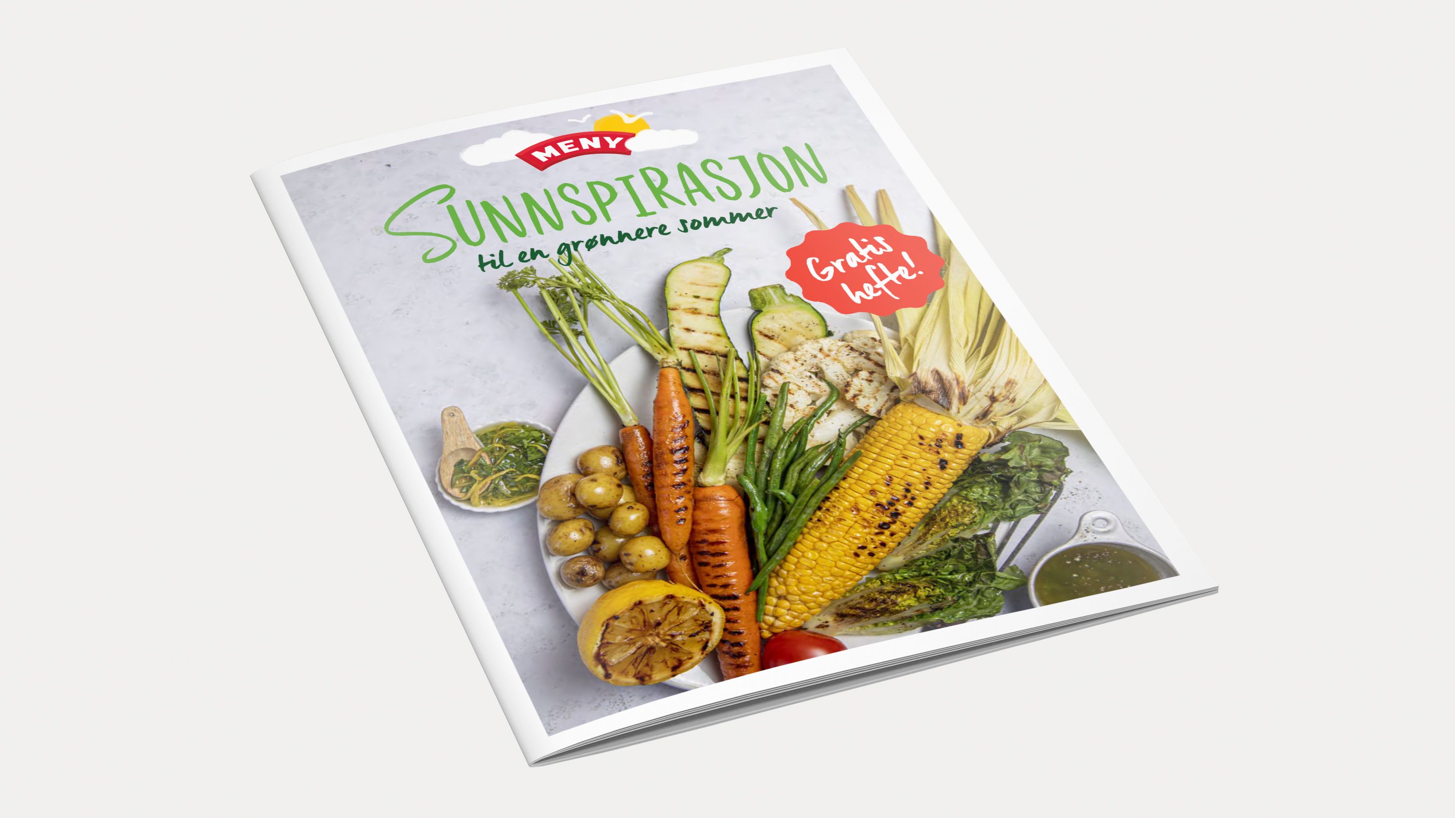 En åpen bok med bilder av ulike grønnsaker og frukt på forsiden, med tittelen 'Sunn inspirasjon' og en rød stjerne som sier 'Ferske oppskrifter'.