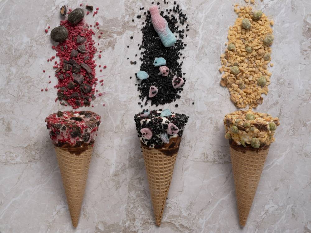 Tre iskremkjeks med ulike toppings og dryss, plassert på en lys overflate.