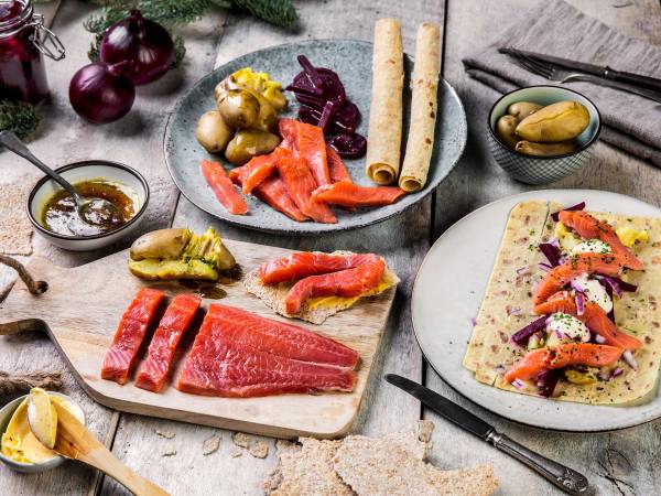 Et utvalg av tradisjonelle juleretter, inkludert rakfisk, flatbrød, og tilbehør som syltetøy og grønnsaker, på et bord.