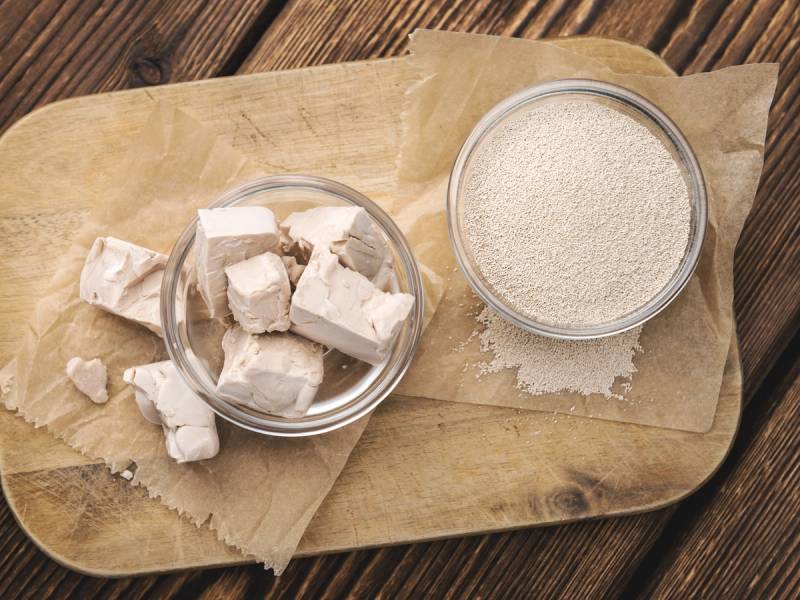 Sukkerbiter og en skål med mel på et papir på et trebord.