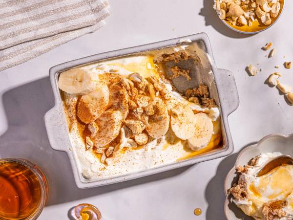 Weetabix med bananskiver og yoghurt i en liten form, med en skål med granola ved siden av.