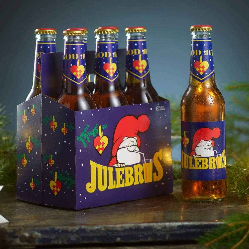 En seks-pakning med julebrus med en enkel juledekorasjon i bakgrunnen.
