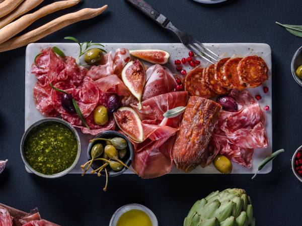 Et utvalg av spekemat, oliven, og fiken på et serveringsfat, klar for helgekos.