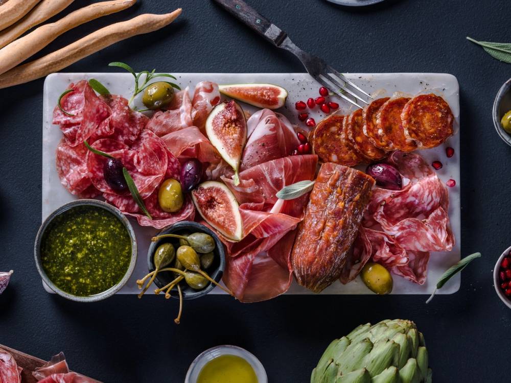 Et utvalg av spekemat, oliven, og fiken på et serveringsfat, klar for helgekos.