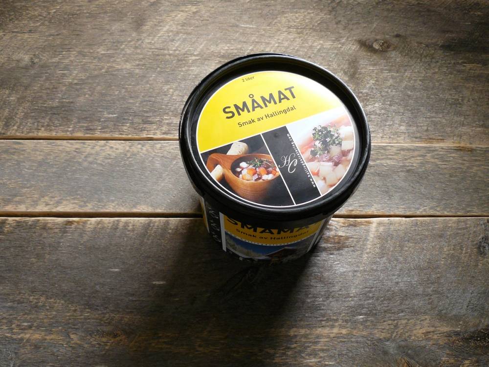 En kopp med iskrem og smågodt på en trebenk, med en etikett som sier 'SMÅMAT'.