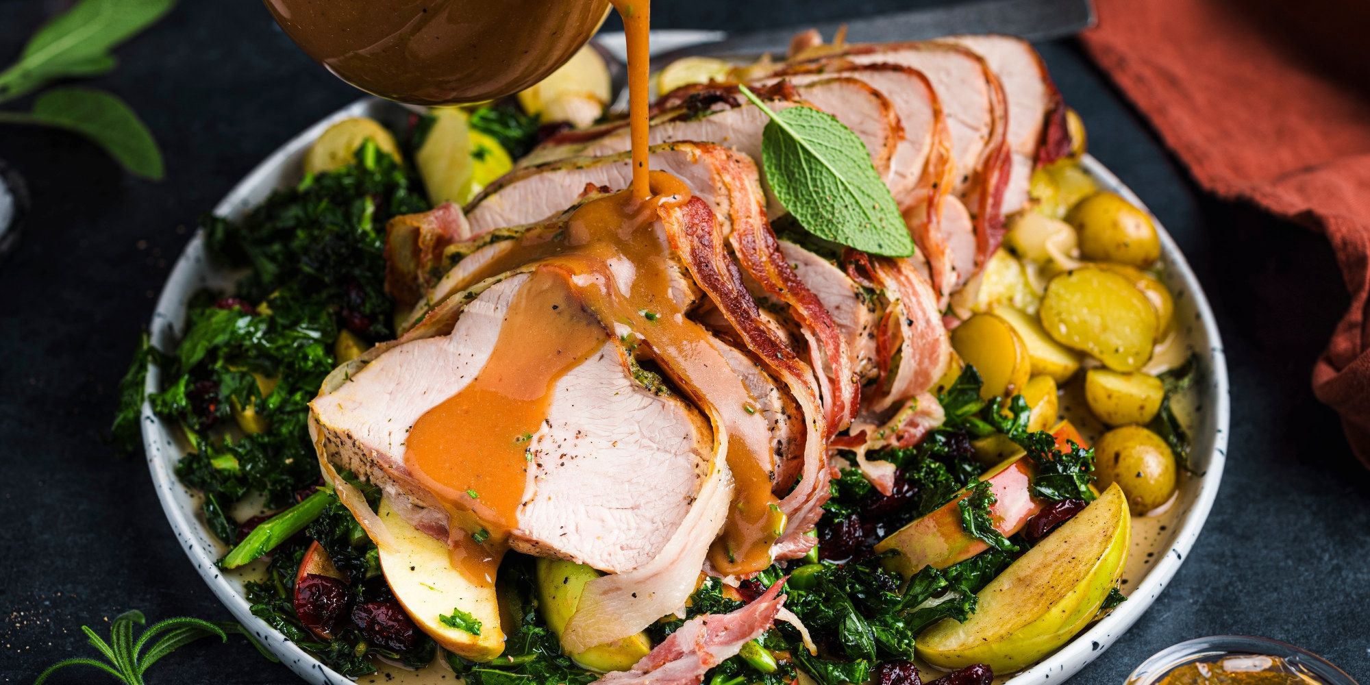 Baconstekt kalkunfilet servert med grønnsaker og poteter på en tallerken.