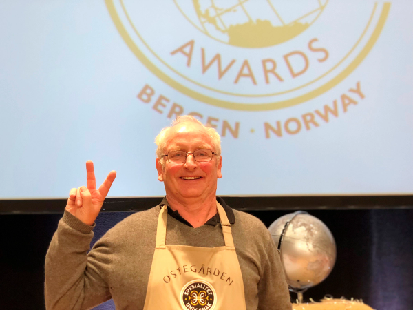 Person med forklær foran en skjerm med teksten 'Awards Bergen Norway'.