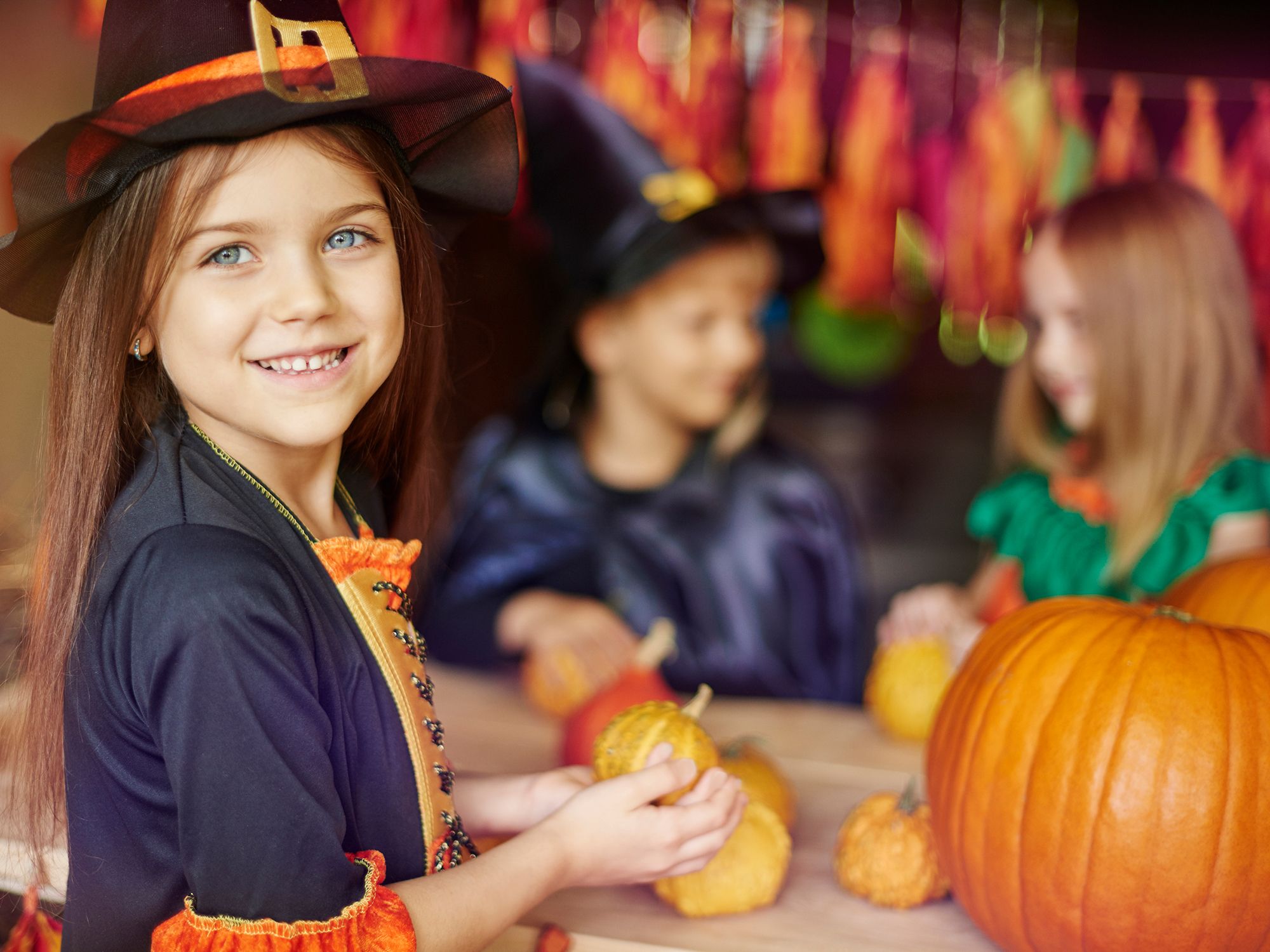 Barn kler seg ut i halloween-kostymer og holder små gresskar på en festlig halloween-feiring.