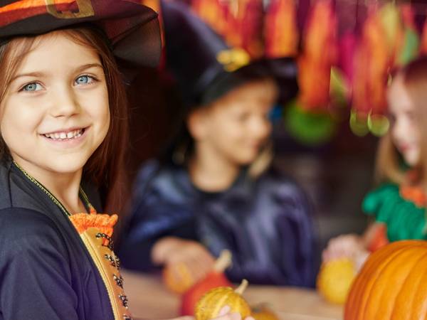 Barn kler seg ut i halloween-kostymer og holder små gresskar på en festlig halloween-feiring.