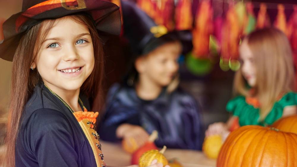 Barn kler seg ut i halloween-kostymer og holder små gresskar på en festlig halloween-feiring.