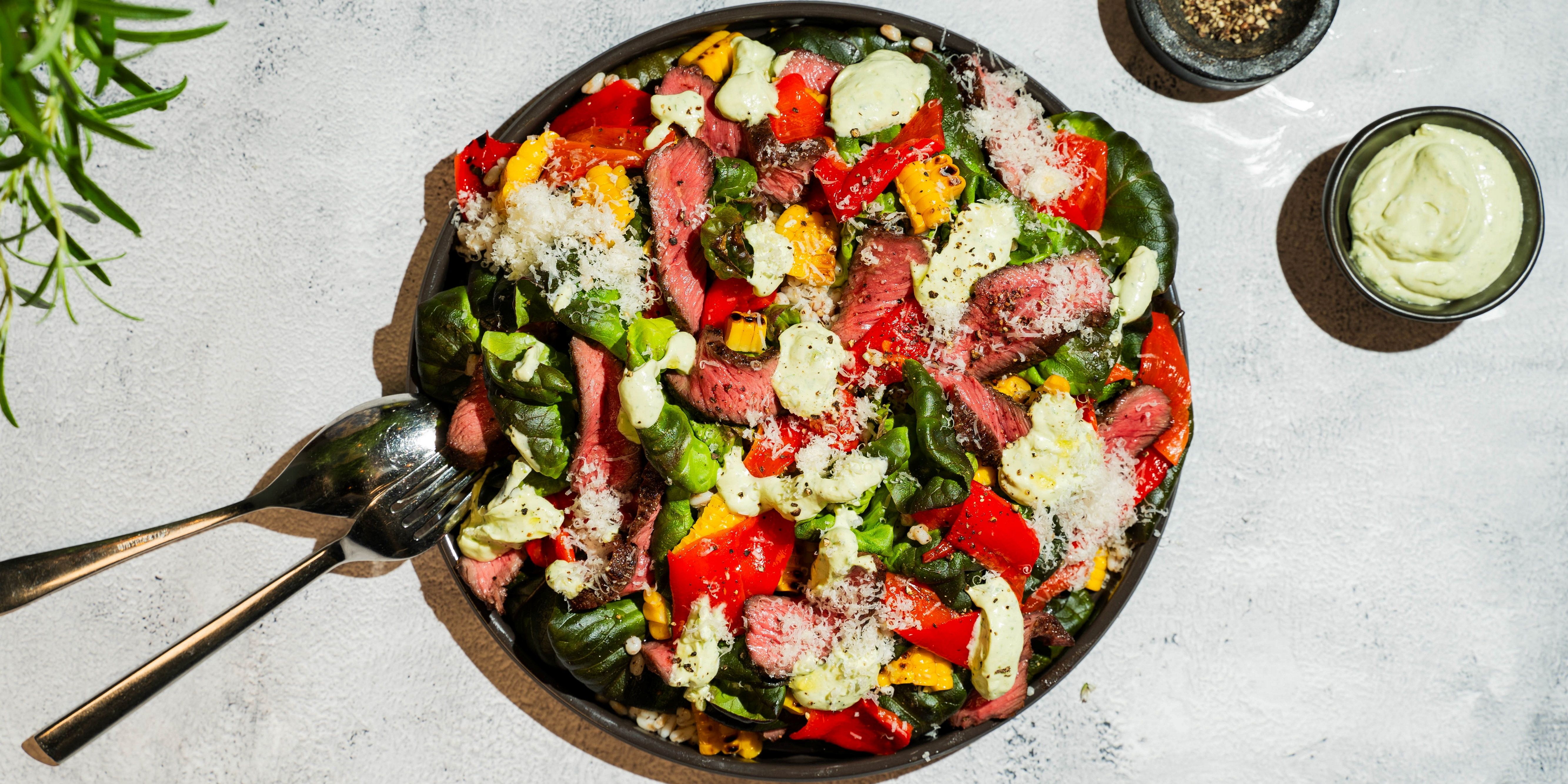 En biffsalat med grønnsaker og spicy avokadodressing i en svart bolle