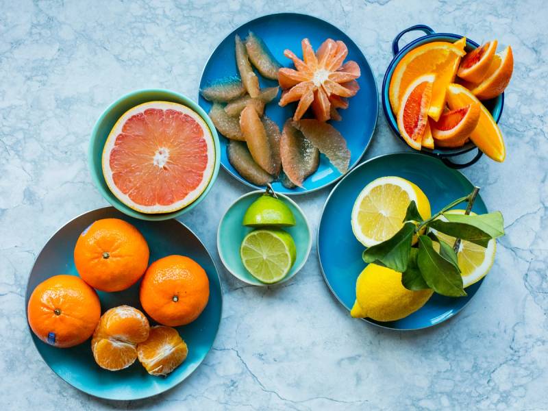 Fargerike skåler med sitrusfrukter og ingefær på et bord.