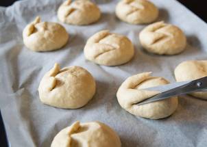 Hjemmelagde påskegodteriboller som er formet og ligger på et bakepapir, med en kniv som former en av bollene.