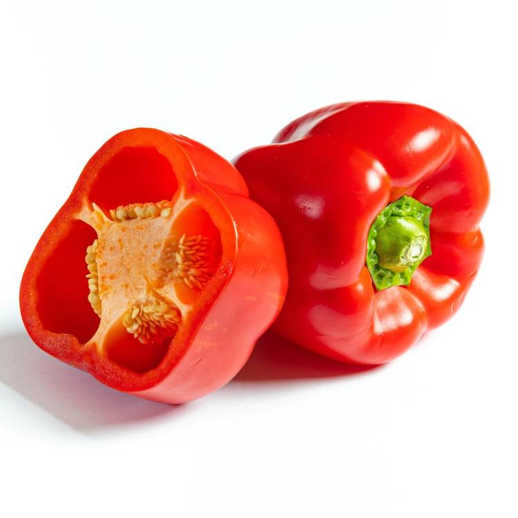 To røde paprika, en hel og en delt, viser innsiden med frø og kjøtt.