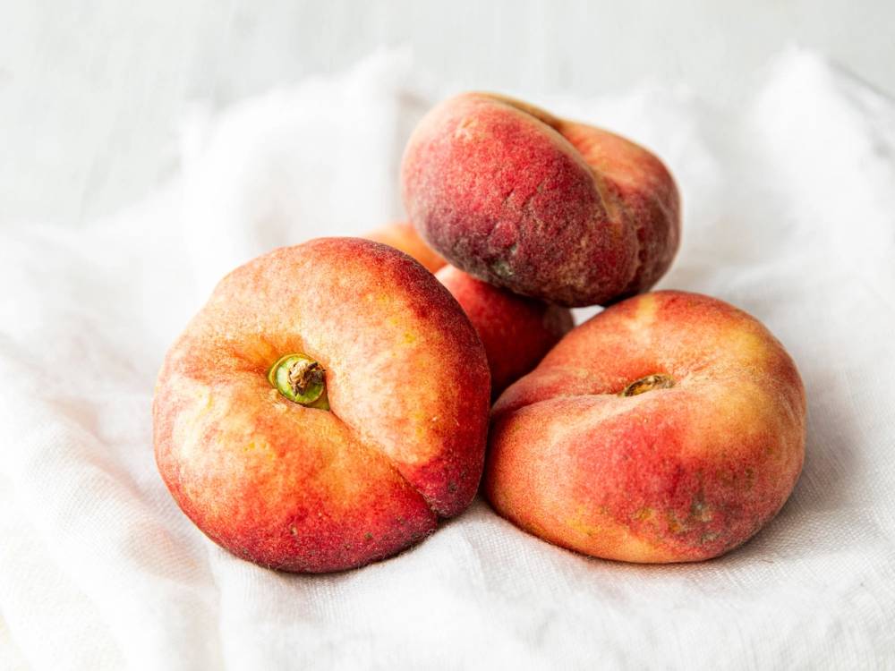 Tre fersken og nektariner ligger på hvitt papir