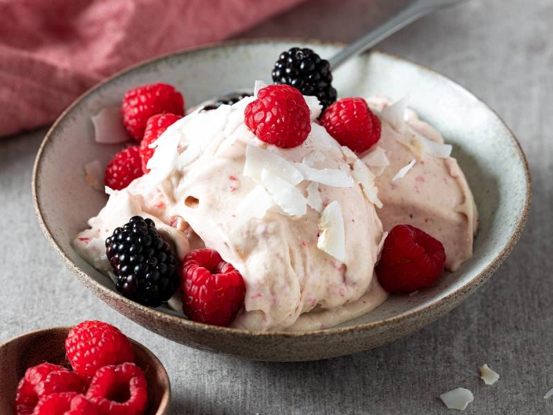 Bringebæris med kokosflak og bær på en skål, med flere bær i en liten skål ved siden av