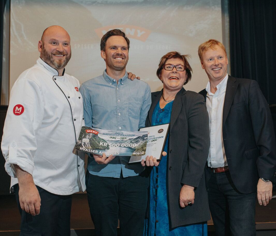En gruppe mennesker står på scenen under en prisutdeling, og en av dem holder et stort sjekk med teksten 'Matskatt vinner 2018'.