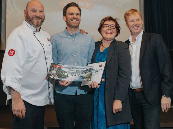 En gruppe mennesker står på scenen under en prisutdeling, og en av dem holder et stort sjekk med teksten 'Matskatt vinner 2018'.