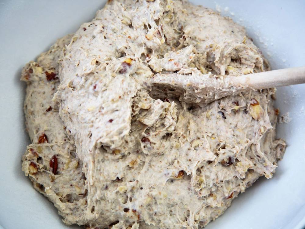 Grovbrøddeig med nøtter som blir rørt sammen i en bolle