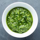 Kremet grønn pesto i en hvit bolle på en grå overflate