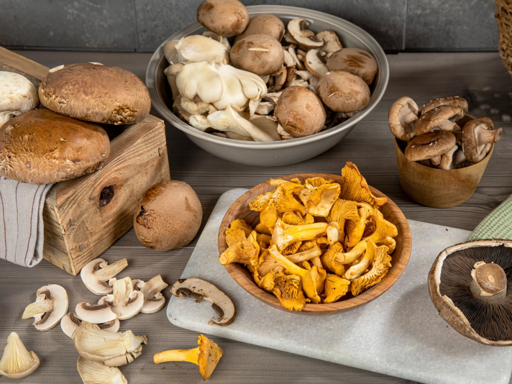 Ulike sopp på tallerkener og i skåler, med noen sopp på et treblokk og rundt på bordet.