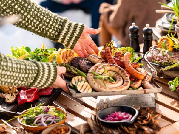 Et bord med et godt utvalg gourmetpølser og tilbehør på en utendørs grilling.