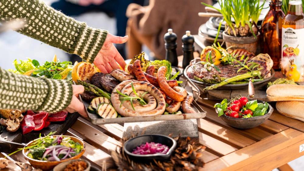 Et bord med et godt utvalg gourmetpølser og tilbehør på en utendørs grilling.