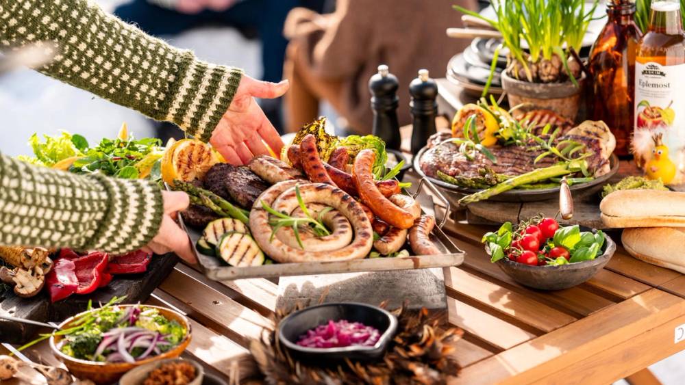 Et bord med et godt utvalg gourmetpølser og tilbehør på en utendørs grilling.