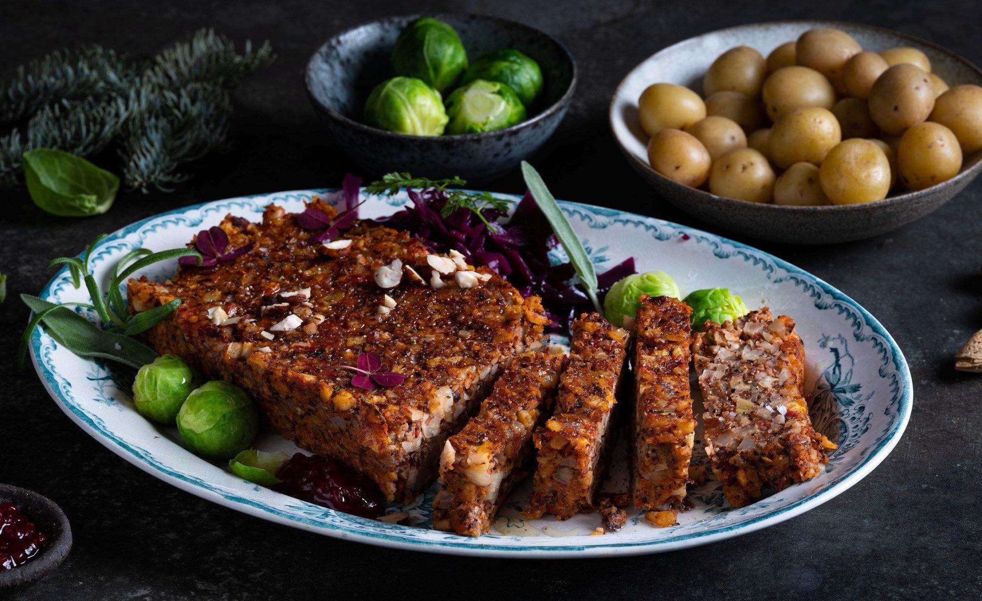 Nøttestek servert på et fat med grønnsaker og tilbehør, omgitt av grønne og brune ingredienser.