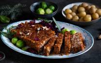 Nøttestek servert på et fat med grønnsaker og tilbehør, omgitt av grønne og brune ingredienser.