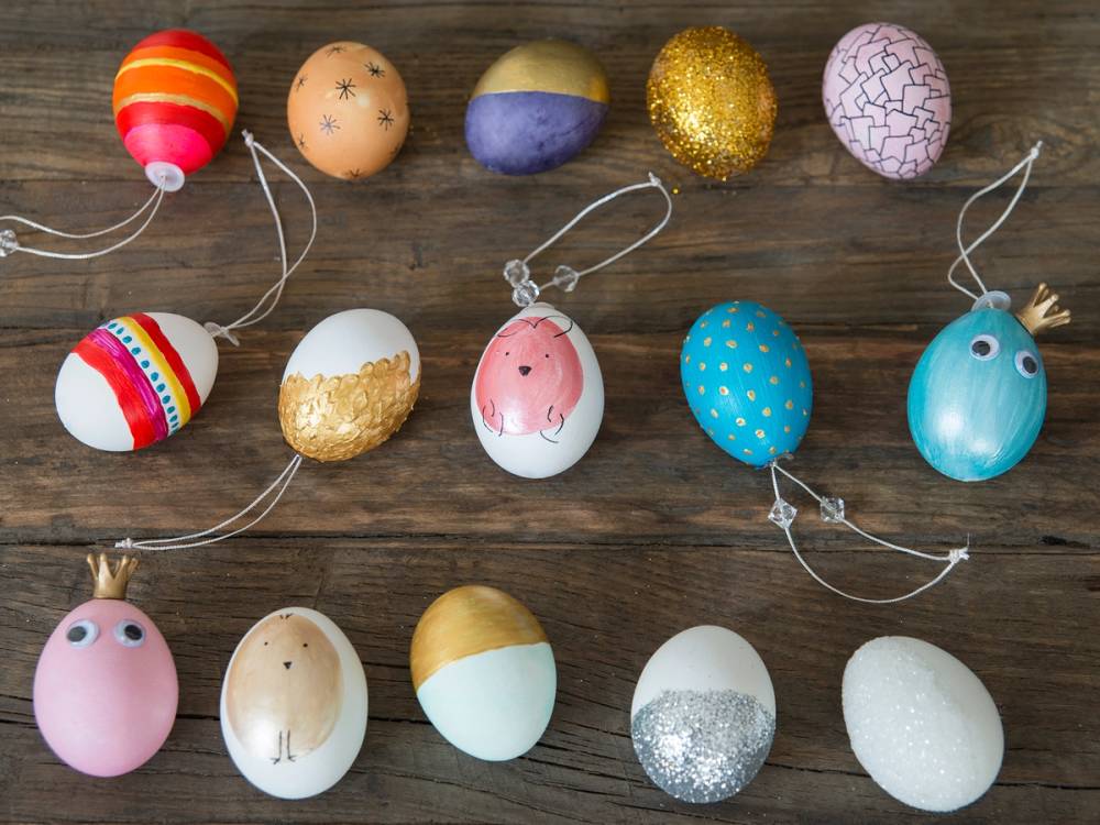 Fargede påskeegg med ulike mønstre og dekorasjoner ligger på en treflate, klare til å bli blåst ut og pyntet til påske.