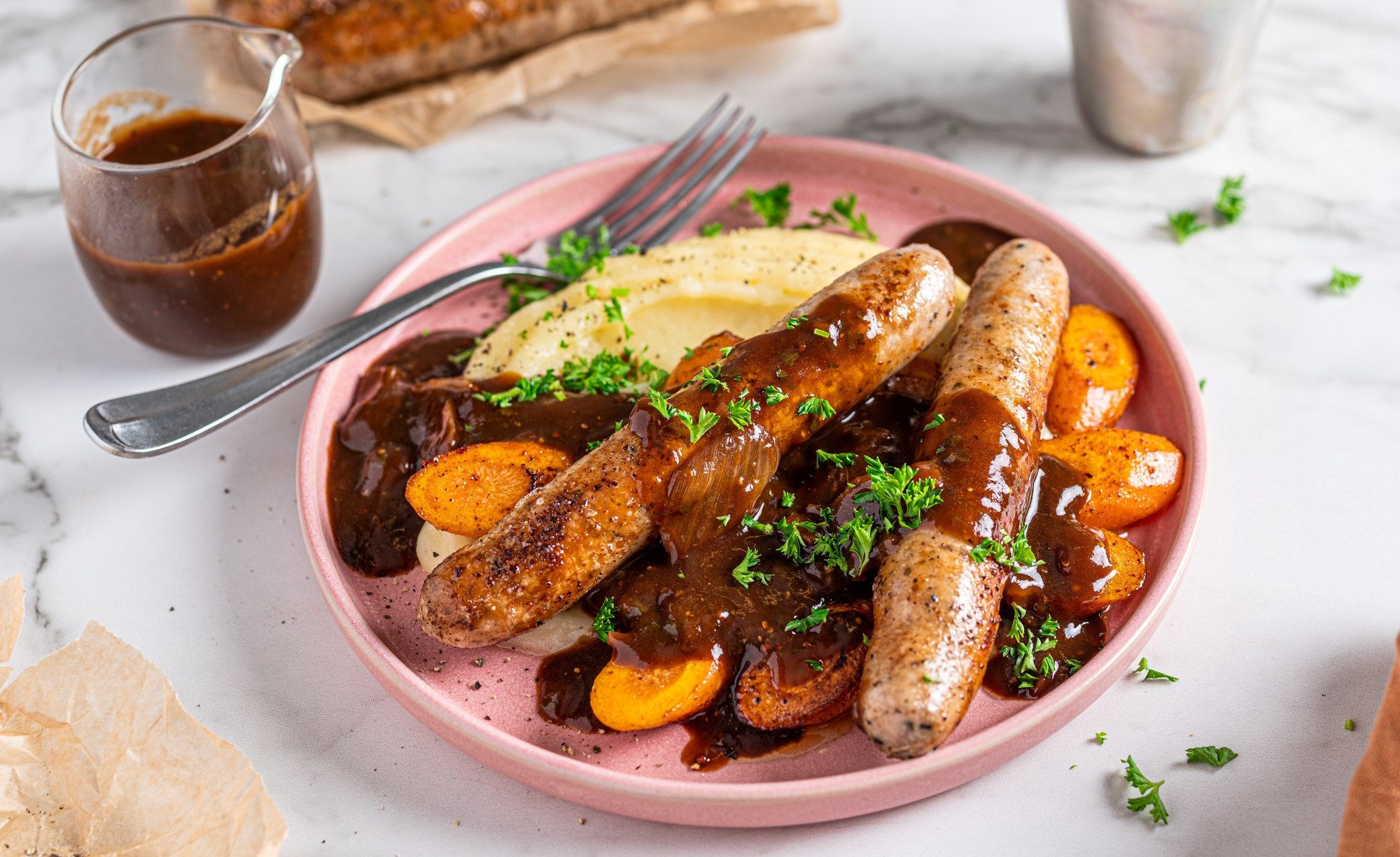 En tallerken med pølser, potetmos, gulrøtter og brunsaus, typisk for ukens middag bangers and mash.