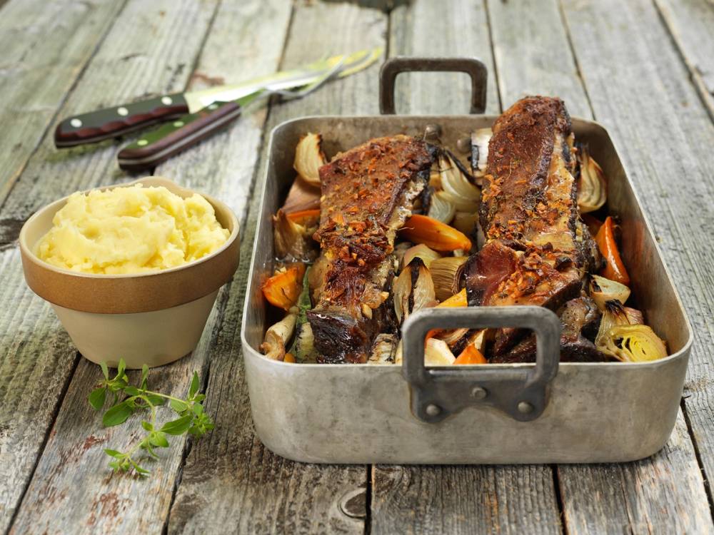 Ovnsbakte bibiringer med grønnsaker i en liten metallform, ved siden av en skål med potetmos, på et rustikt trebord.