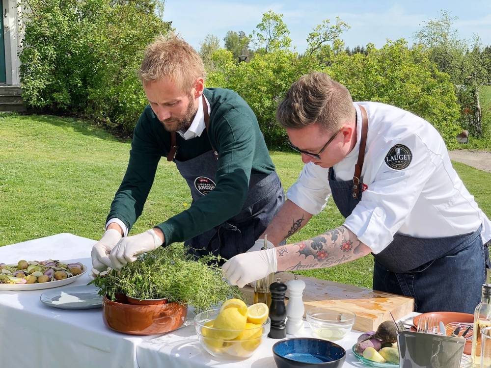 To personer lager mat utendørs på en hagefest, med grønne trær i bakgrunnen.
