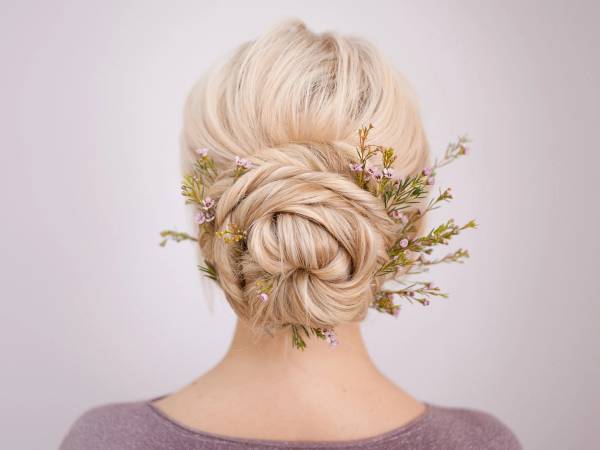 En person med lyst, oppsatt hår dekorert med små blomster og grener sett bakfra.