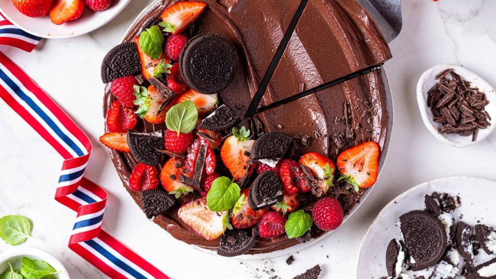 En sjokolademousse-kake pyntet med friske bær og mynteblader, med en skje på siden.