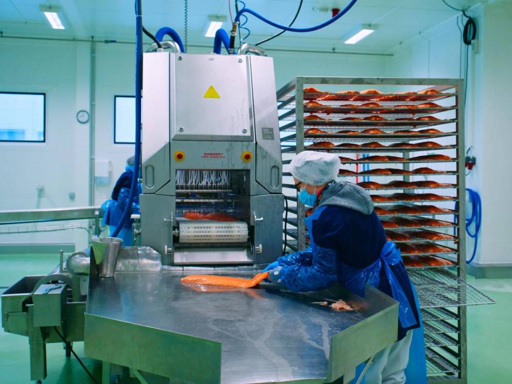 Person kontrollerer kvalitet før laksefileten legges på rist.