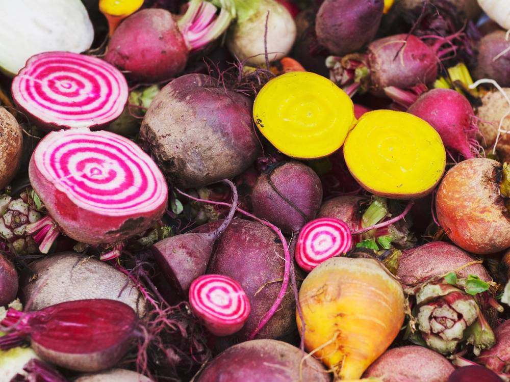 Fargerike rotgrønnsaker, inkludert rødbeter og gulrøtter, ligger i en haug.