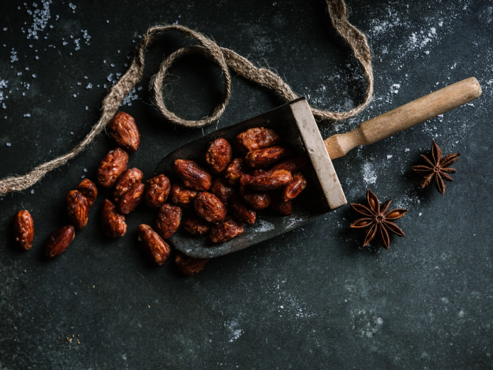 Tørkede dadler og stjerneanis på en mørk overflate med en liten hammer og en snor, som kan være til julestemning eller matlaging.