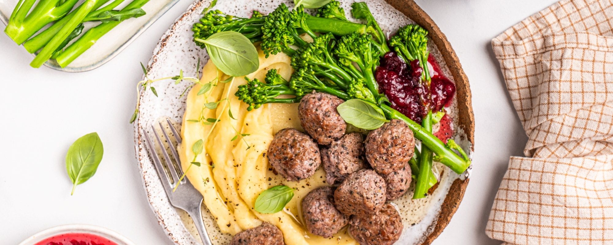 Kjøttboller med potetmos og grønnsaker på en tallerken.