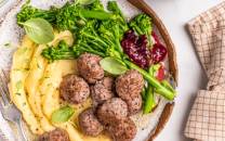 Kjøttboller med potetmos og grønnsaker på en tallerken.