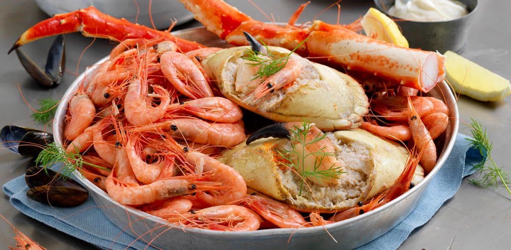 En tallerken med kokte skalldyr, inkludert reker og hummer, pyntet med urter.