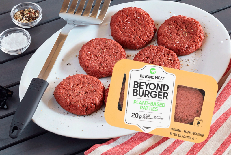 Fire plantebaserte burgerpatties på en hvit tallerken med krydder og en pakke merket 'Beyond Burger'