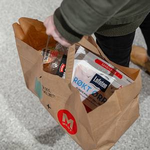 Person som holder en papirpose med matvarer fra Too-good-to-go, sett ovenfra.