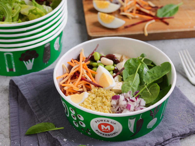 En salat med spinat, egg, grønnsaker og couscous i en grønn salatbar-kopp.