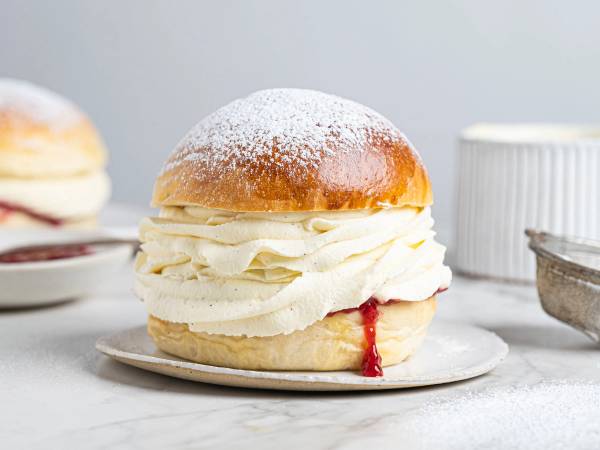 En fastelavnsbolle fylt med krem og syltetøy, pyntet med melis på toppen.